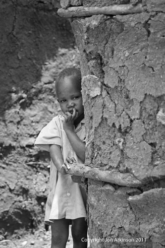 Child outside of dung covered hut, Kenya. Child outside of dung covered hut, Kenya.